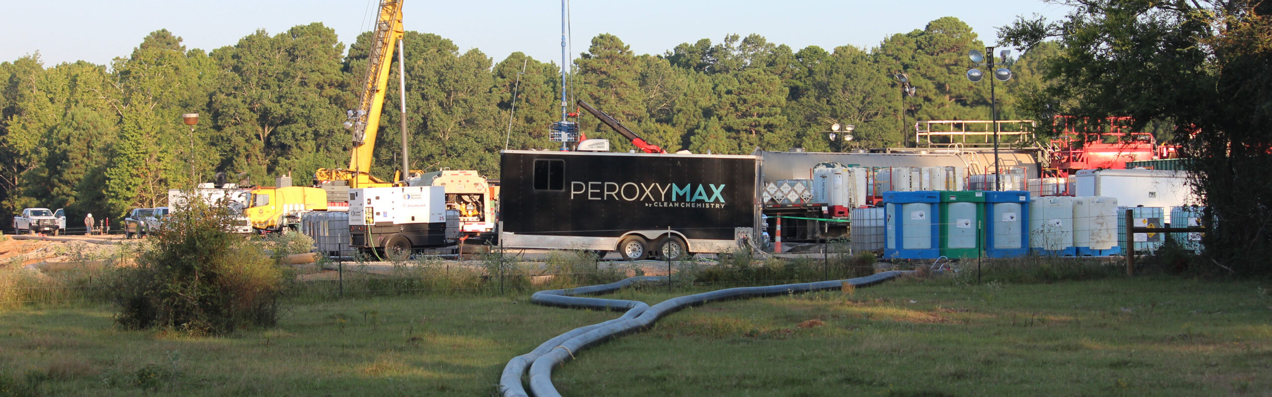 A treatment trailer sits in a field during sunset at a hydraulic fracturing site