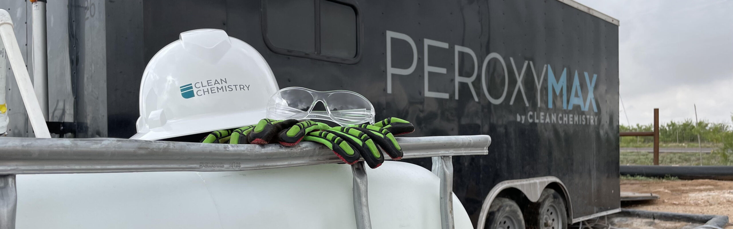 Safety gear sits on a tote next to a PeroxyMAX treatment trailer